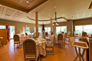 a dining room with tables and chairs and windows at Hotel-restaurant Les Caudalies in Arbois