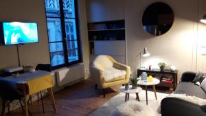 a living room with a couch and a tv at L'Echiquier de Normandie confort cosy et vue premium in Rouen