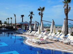 a row of lounge chairs next to a swimming pool at Fantasy Beach Apartment in Golem