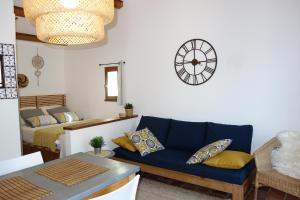 a living room with a couch and a clock on the wall at Gîte Marius in Mirabel-aux-Baronnies