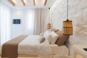a white bedroom with a large bed and two pendant lights at Villa Adriana Hotel in Agios Prokopios