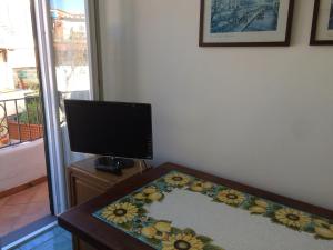 a living room with a tv and a table with a carpet at LA CASETTA DI ERIKA in Lacco Ameno