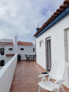 un balcón con 2 sillas blancas en un edificio blanco en Casa Furt@do, en Burgau