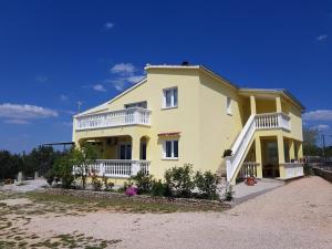 a large yellow house with white balconies at Apartmani Marijana in Lozovac