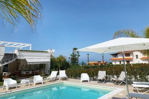 a pool with chairs and an umbrella next to a house at Centurio luxury rooms in Tropea