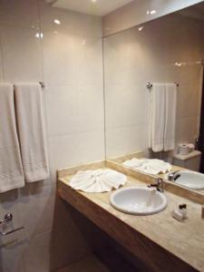 a bathroom with a sink and a mirror and towels at Apart Hotel Acrópolis in Santana do Livramento