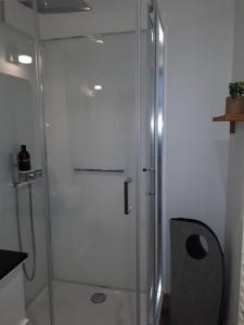 uma cabina de duche em vidro numa casa de banho com uma cadeira em Un Appart en Ville em Niort