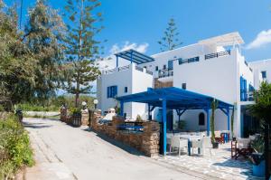 a white building with a blue umbrella in front of it at Villa Adriana Hotel in Agios Prokopios
