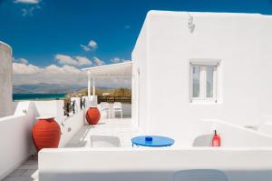 a white balcony with orange vases and chairs at Villa Adriana Hotel in Agios Prokopios