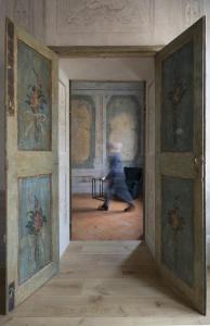 a person walking through a room with paintings on the walls at Appartamento affrescato 180mq in palazzo del 600 a Mantova in Mantova