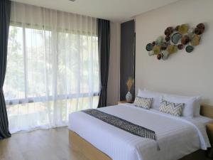 a bedroom with a large bed and a large window at CHUZ Villas Samui SHA Plus in Lamai