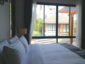 um quarto com uma cama grande e uma janela grande em CHUZ Villas Samui SHA Plus em Lamai
