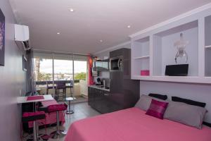 a bedroom with a pink bed and a kitchen at Port Nature Village Naturiste in Cap d'Agde