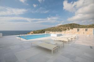 a pool with white benches on the roof of a building at Villa Athina in Ambrami