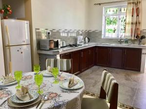 a kitchen with a table with chairs and a refrigerator at Cardamon Villa is a 2 bedroom with 1 bathroom and seperate toilet detached house with AC and swimming pool , 5 minutes walk from Flic en Flac public beach in Flic-en-Flac