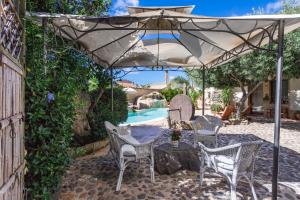 a patio with a table and chairs under an umbrella at Hotel Villa Canu in Càbras