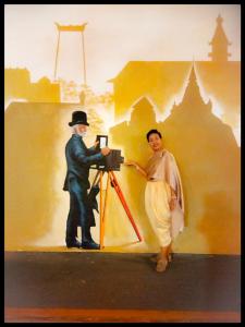 een schilderij van een man die een foto van een vrouw neemt bij Café de Baan Raow in Bangkok