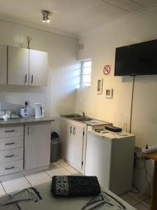 a small kitchen with white cabinets and a stove at The Lighthouse Guesthouse in Welkom