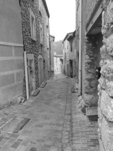 an empty alley with a stone building and a brick street at Les lavandes in Duilhac