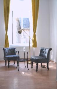 two chairs and a table in a room with a window at BpR Auric Home in Budapest
