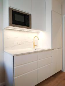 biała kuchnia ze zlewem i kuchenką mikrofalową w obiekcie Two-bedroom apartment 'Taupé' w Wiedniu