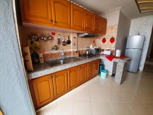 cocina con armarios de madera, fregadero y nevera en App Khouribga, en Khouribga