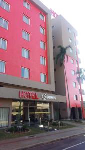 a red hotel with a palm tree in front of it at Dunamys Hotel Londrina in Londrina