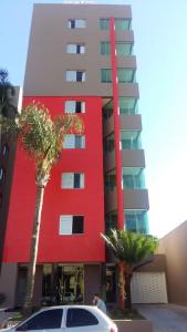 a red building with palm trees in front of it at Dunamys Hotel Londrina in Londrina