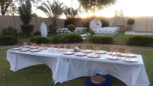 a white table with glasses and plates on it at Fahms in Letlhakane