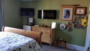 a bedroom with a bed and a dresser and a television at Bondy House Bed & Breakfast in Amherstburg