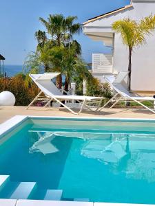 a swimming pool with two lounge chairs next to a house at Centurio luxury rooms in Tropea