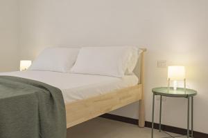 un letto con lenzuola bianche e una lampada su un tavolino di Cortile Baronello a Agrigento