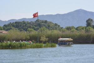 a boat with a red flag on a river at B&B Boutique Hotel in Dalyan