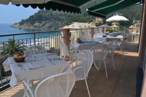 un restaurante con mesas y sillas blancas y el océano en Hotel Delle Rose, en Bonassola