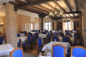 uma sala de jantar com mesas brancas e cadeiras azuis em Vettonia em Ávila