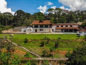ein Haus auf einem Hügel mit einem grünen Hof in der Unterkunft Guest House Nosso Aconchego in Teresópolis