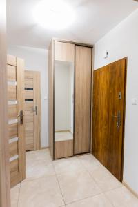 um quarto vazio com portas de madeira e pisos de azulejo em Apartament 3d Szczecin em Szczecin