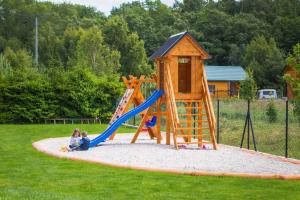two children playing on a playground with a slide at Przystań Domki w Lubiatowie in Lubiatowo