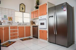 una cocina con nevera de acero inoxidable y armarios naranjas en Villa Fleur De Mer Sint Maarten, en Upper Princeʼs Quarter