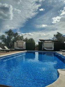 une grande piscine bleue avec des chaises et un ciel nuageux dans l'établissement Agroturismo Sa Vinya d'en Palerm, à Sant Miquel de Balansat