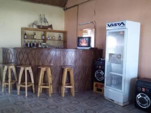 eine Bar mit einer Reihe von Hockern und einem Kühlschrank in der Unterkunft Chez Zizou Manakara in Manakara