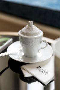 a white cup and saucer with a spoon on a table at Parisii Luxury Relais Rome in Rome