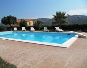 a swimming pool with lounge chairs and a house at Agriturismo Ghiritina in Francavilla di Sicilia