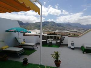 a balcony with a table and chairs and an umbrella at Habitación con baño privado in Gáldar +42 photos
