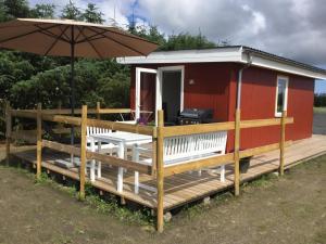 een tiny house met een paraplu en een terras bij Feriehytten Hønsehuset in Løkken