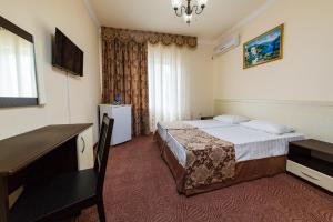 アナパにあるGuest house Tashirのベッドとデスクが備わるホテルルームです。