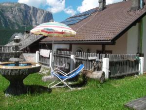 a chair and an umbrella in front of a house at Appartamenti Suttru in Badia
