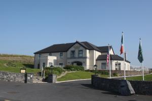 duży dom z dwoma flagami przed nim w obiekcie Vaughan Lodge Hotel w mieście Lahinch