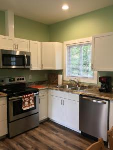 La cuisine est équipée de placards blancs et d'un four avec plaques de cuisson noires. dans l'établissement Brookside Cottages, à Waynesville