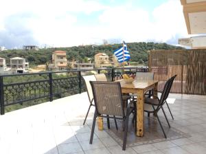 a wooden table with chairs and a flag on a balcony at Anatoli View in Agia Marina Nea Kydonias